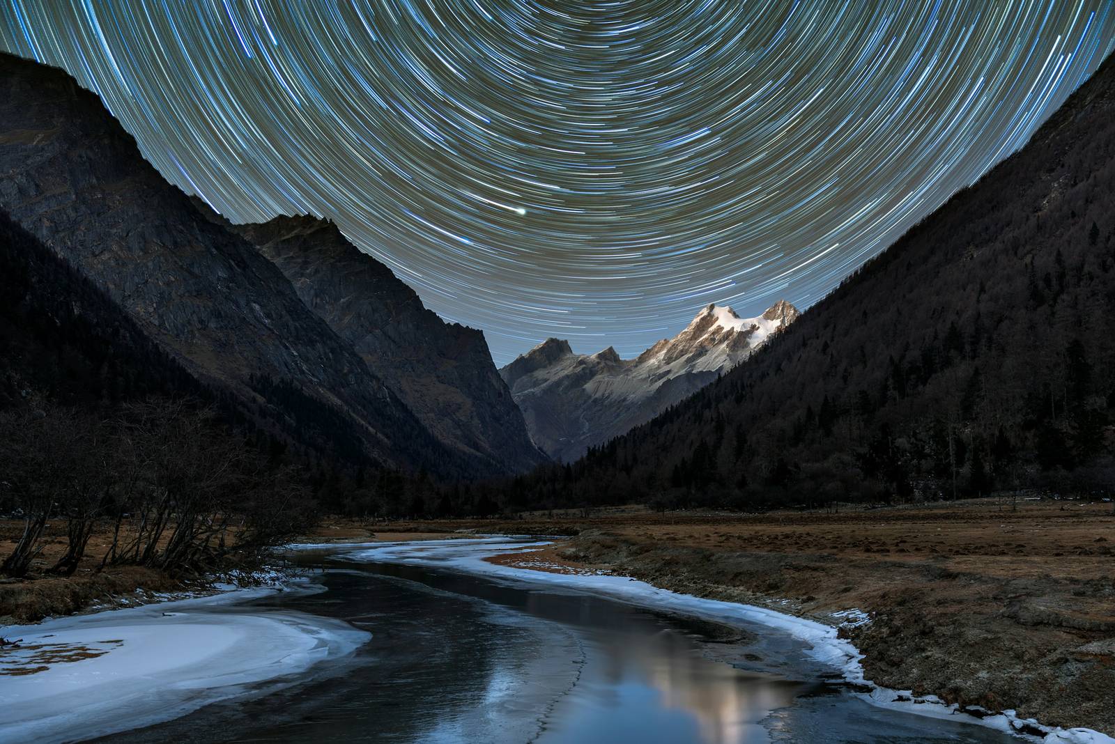 Filé d'étoiles en cercles au-dessus d'une vallée de montagne, photographié en pose longue